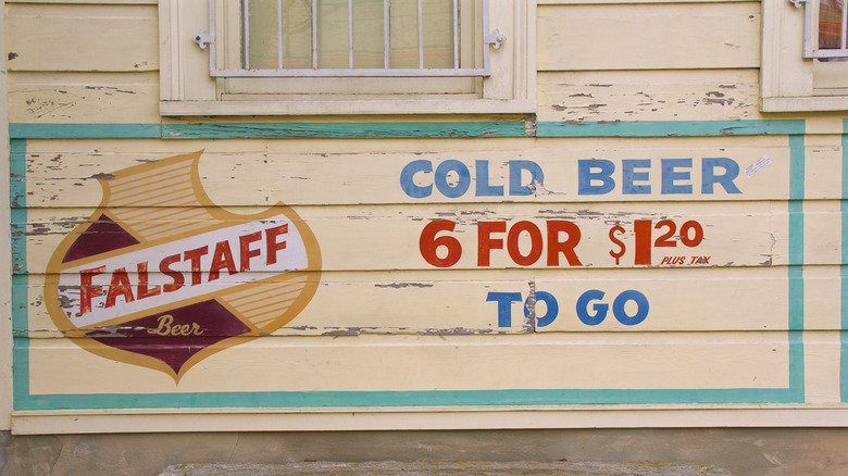 A Falstaff beer sign and logo on wood siding