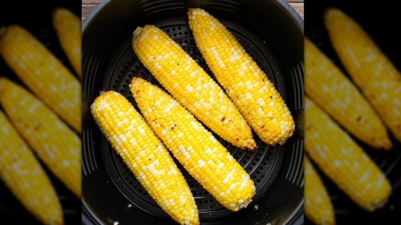 Golden bi-color corn rests in an air fryer basket with toasted kernels.