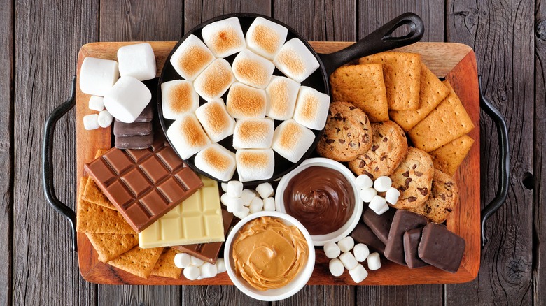 tray of ingredients to make s'more's, including marshmallows, chocolate, and cookies