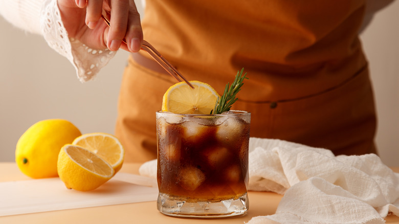 barista putting a lemon slice in a small glass of coffee