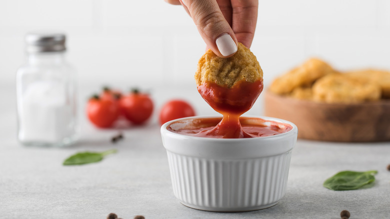 Dipping nugget into cup of ketchup