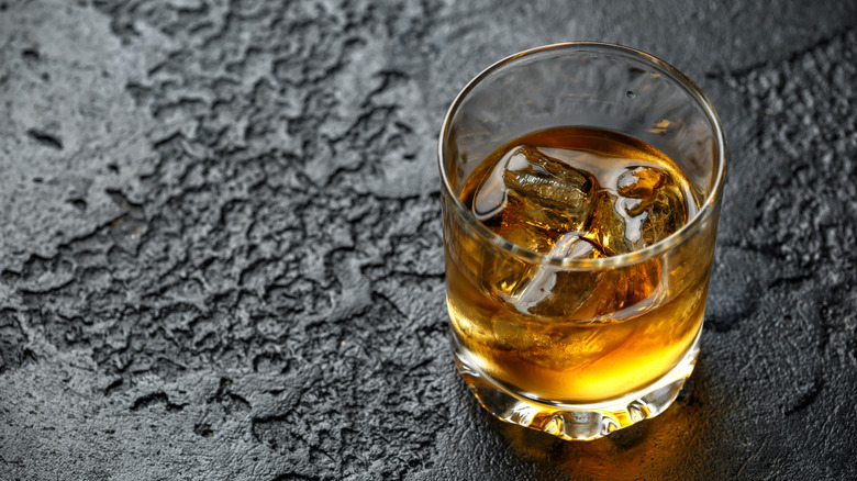 glass of bourbon against a dark stone background