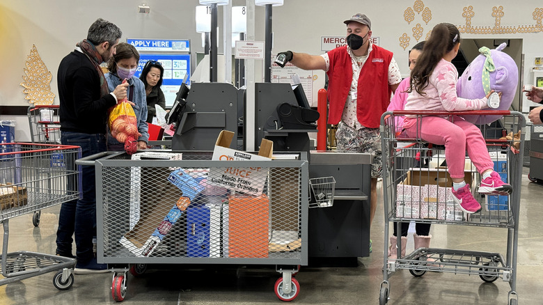 Costco employee and customers at checkout station.