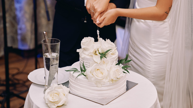 A bride and groom cut a tiered wedding cake