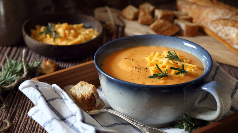 Thick pumpkin soup with crusty bread served in blue and white ceramic mug.