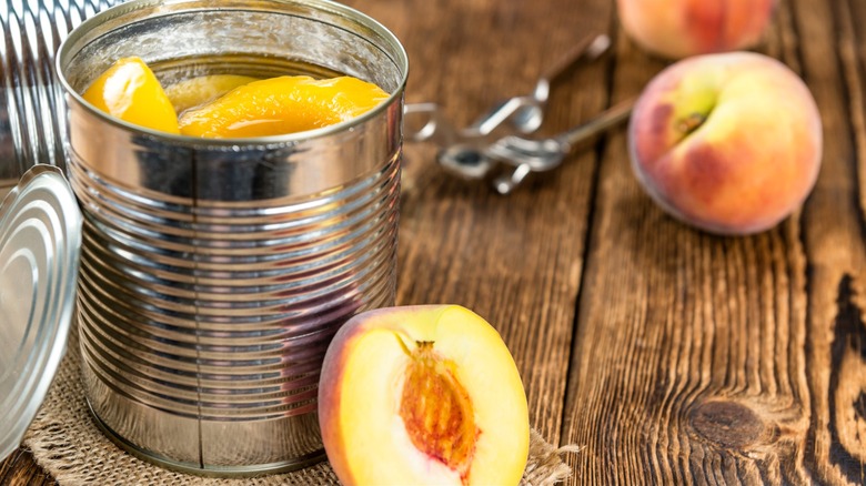 Canned peaches next to fresh on wood table