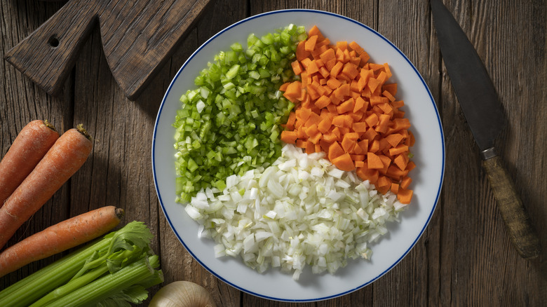 Diced celery, onion, and carrot on a plate in thirds