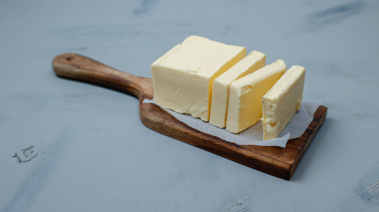 Sliced butter on wood cutting board