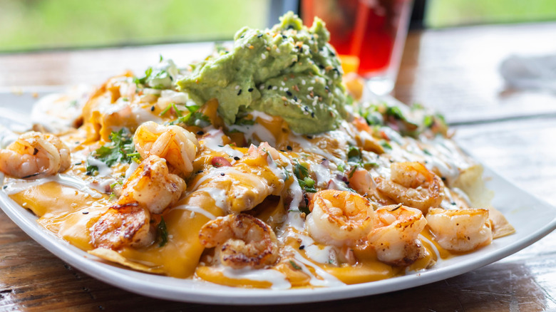 Very cheesy nachos topped with shrimp and avocado