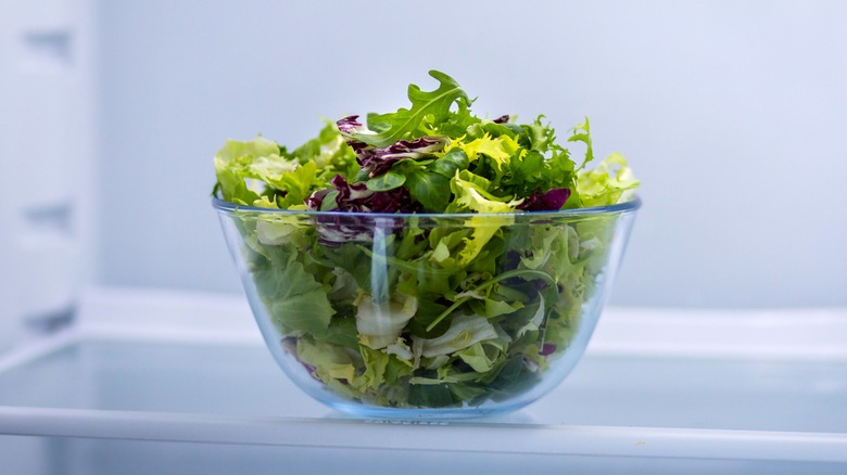 Mixed greens in salad bowl inside refrigerator