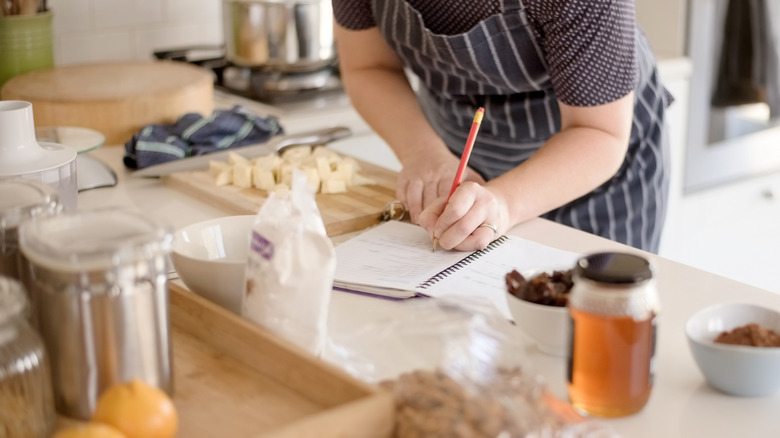 A person writing down a recipe in the kitchen