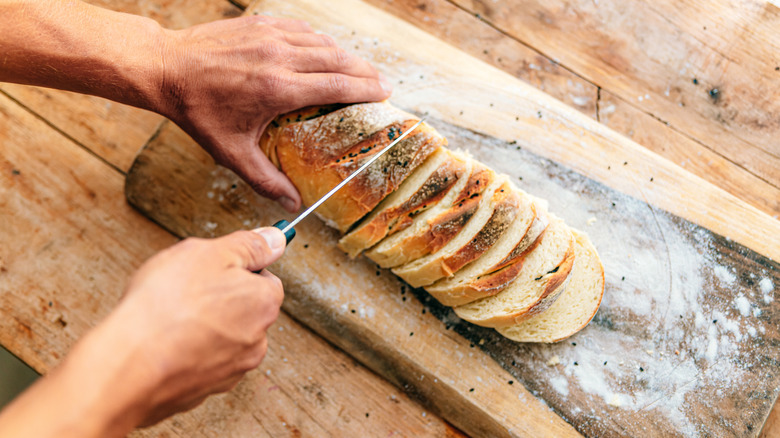 A person cutting a loaf of bread