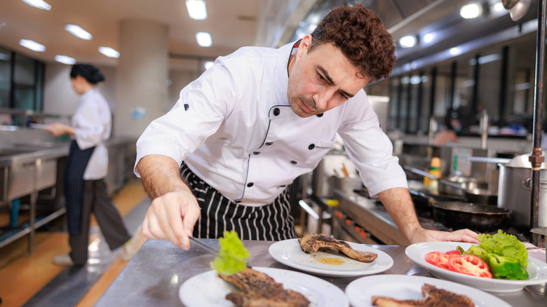 A chef garnishing steaks