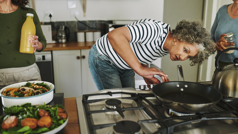 A woman turning on the burner to preheat a pan