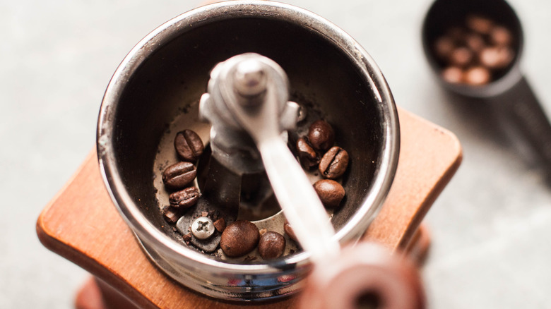 A top-down close up of coffee beans in a hand grinder