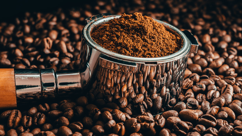 close up of ground coffee in a portafilter, sitting on top of a pile of coffee beans