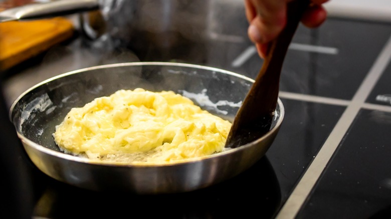 stirring scrambled eggs in pan