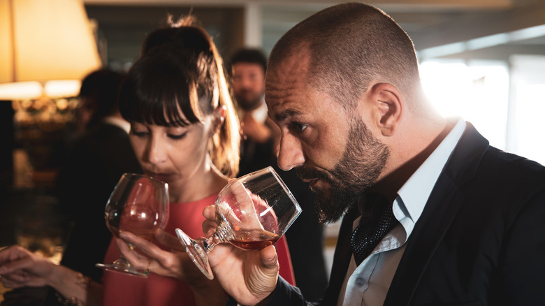 two people smelling whiskey glass