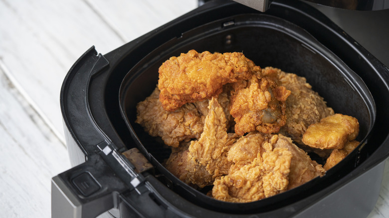 Fried chicken pieces inside an air fryer basket