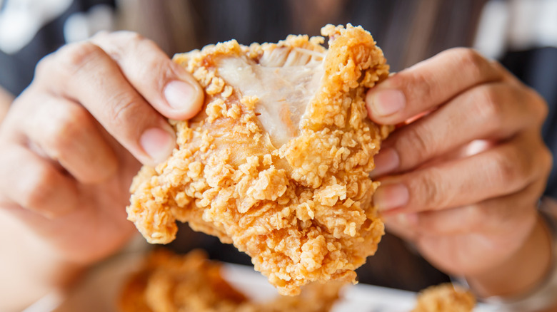 close up of a piece of fried chicken being pulled apart