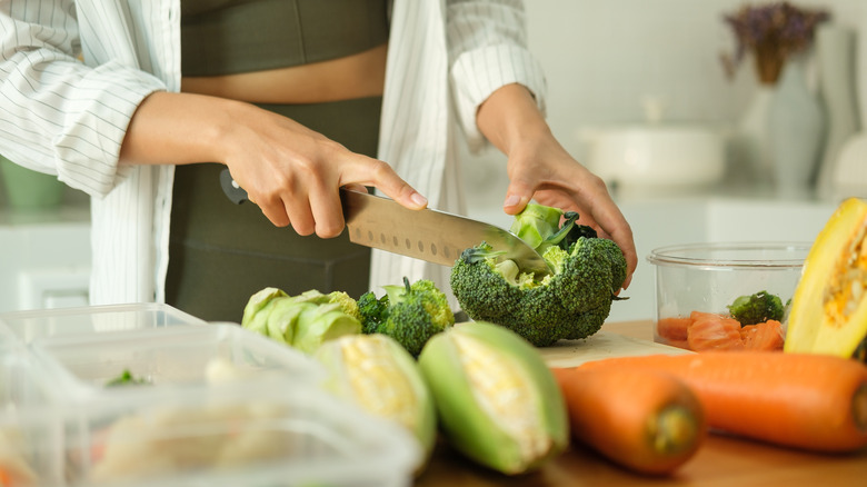 A woman chopping vegetables on a cutting board.