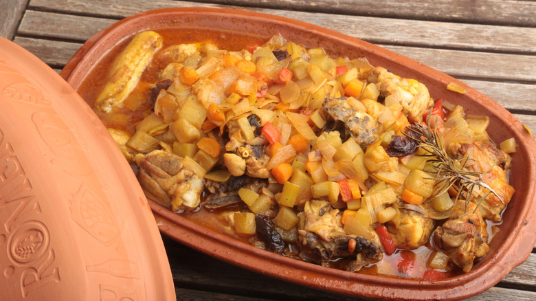 Chicken and veggies in a Römertopf on wood table