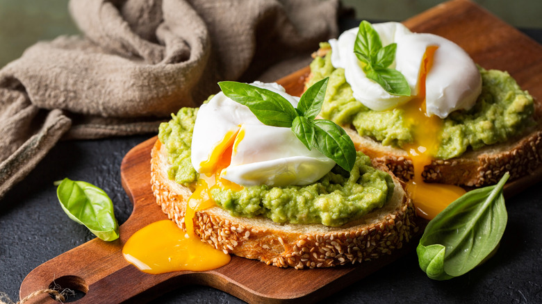 Two runny poached eggs on two slices of avocado toast