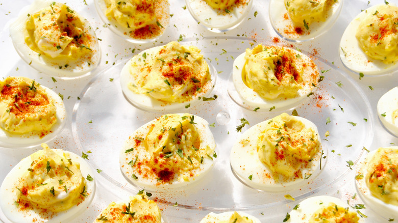 Deviled eggs on clear plate, spices and seasonings on top