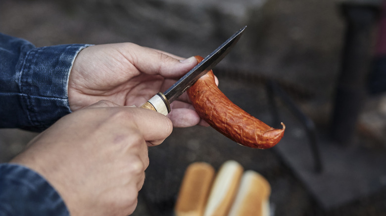 A person cutting a hot dog