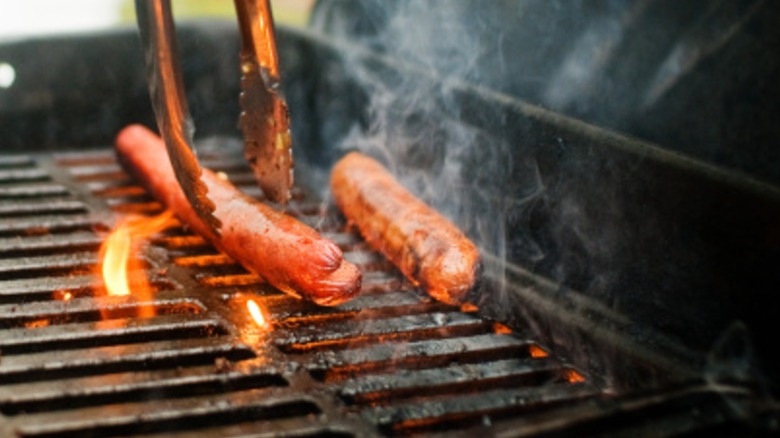 Two hot dogs over flames on a grill