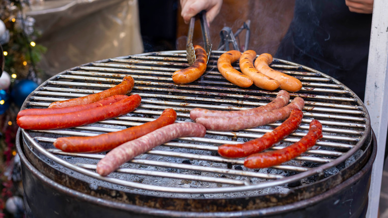 A person cooking hot dogs on a grill