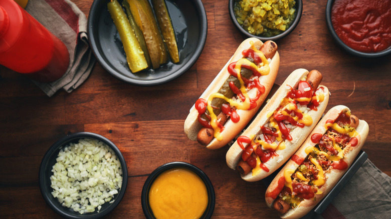 Three Chicago-style hot dogs with condiment cups