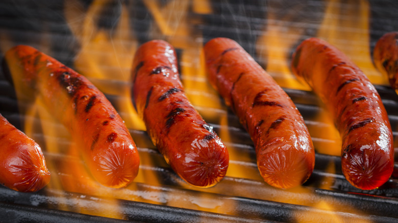 Hot dogs over flames on a grill