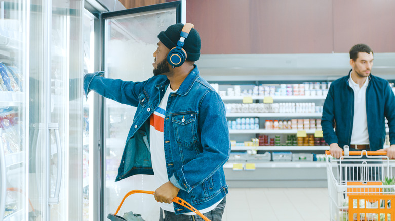 Man in freezer aisle listening to music on headphones