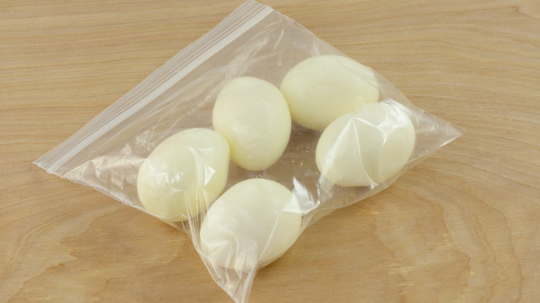 Hard-boiled eggs in plastic bag on wood table
