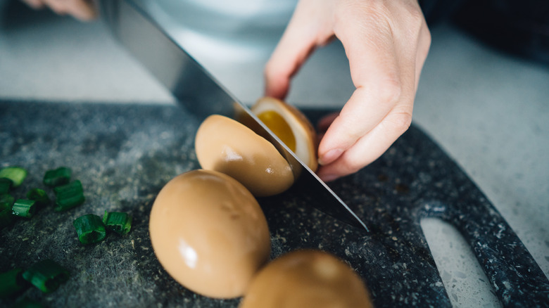 cutting a hard boiled egg on chopping board