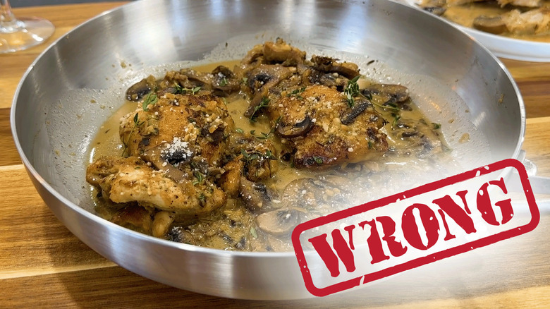 Chicken with sauce and seasonings in a stainless steel pan.