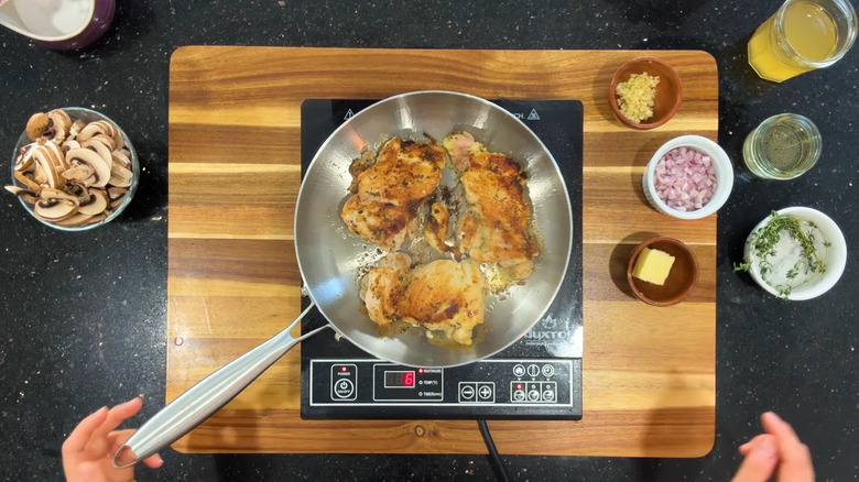 Light brown caramelized chicken sitting in a stainless steel pan.