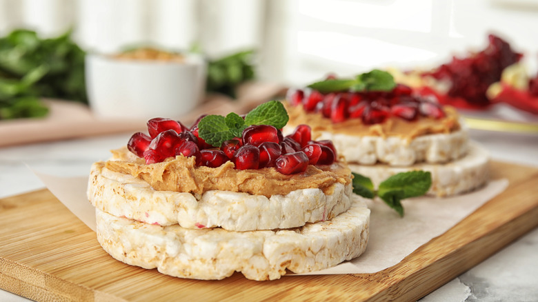 Rice cakes topped with peanut butter, pomegranate seeds, and mint.