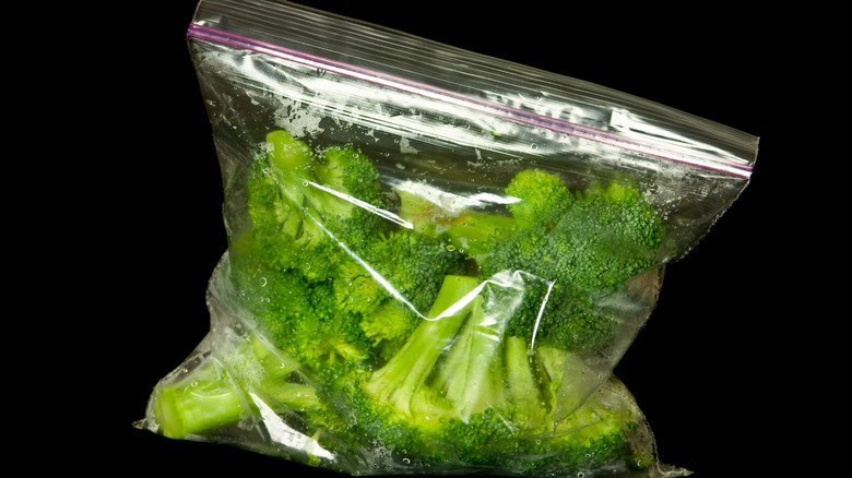 Freezer bag of broccoli florets against black background