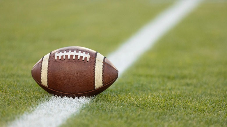 A football sits on a yard marker on a field