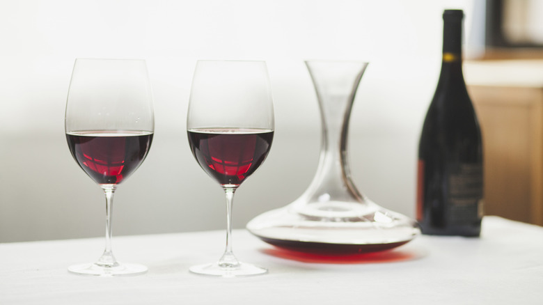 Red wine in glasses next to decanter and bottle.