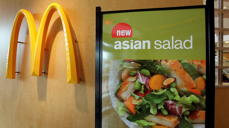 Sign promoting McDonald's asian salad next to the golden arches