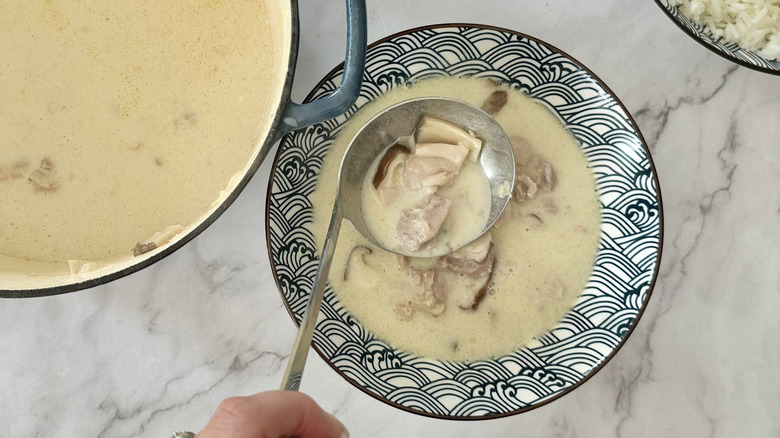 hand ladling soup into bowl