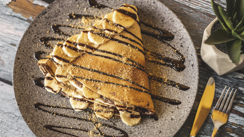 French crepe with bananas and drizzles with chocolate sauce