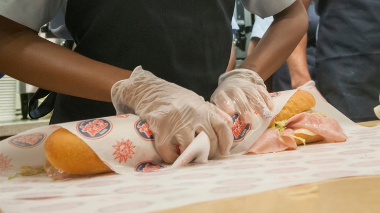 Employee at Jersey Mike's wrapping sub sandwich in paper