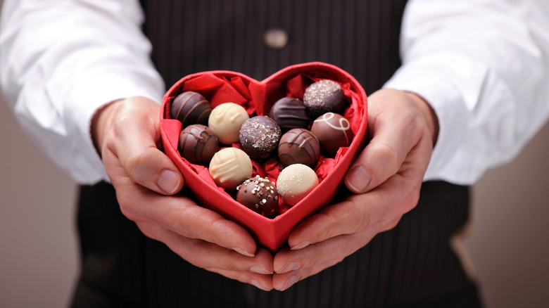 man holding a heart-shaped box of chocolates