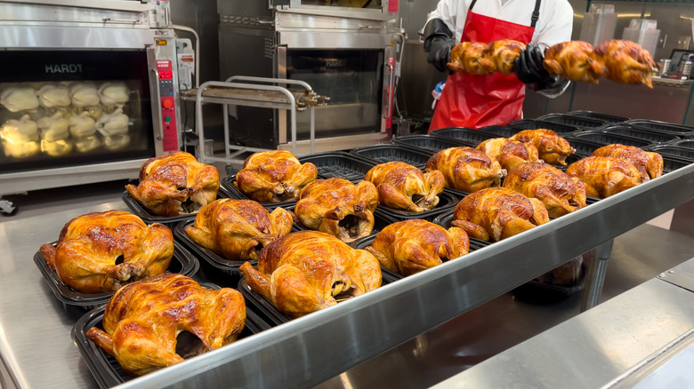 Freshly prepared Costco rotisserie chickens in black containers.