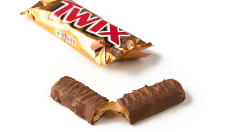 Twix candy bar split in half with wrapper in background