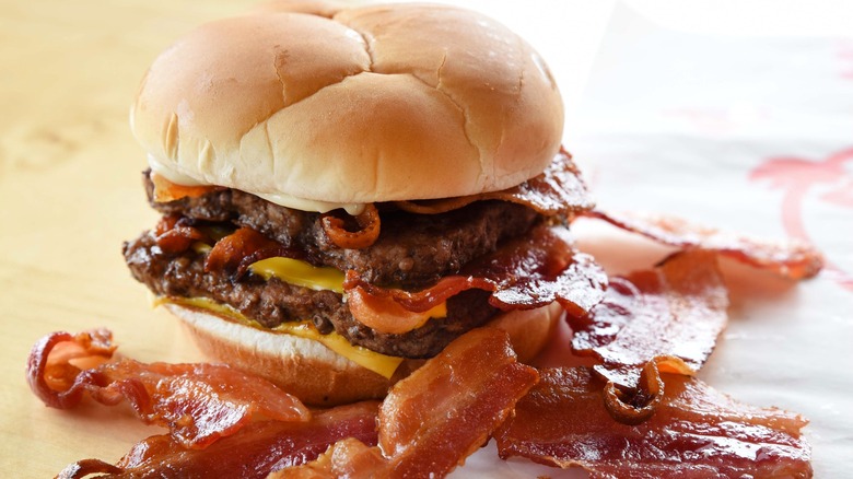 Wendy's Baconator with bacon slices in foreground